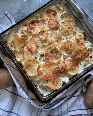 Top view of baking dish filled with golden brown cheesy sliced potatoes.