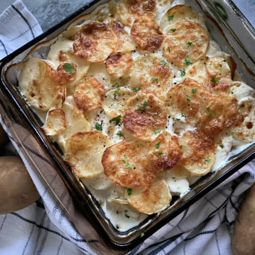 Top view of baking dish filled with golden brown cheesy sliced potatoes.