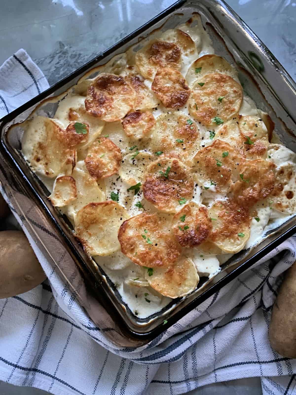 Top view of baking dish filled with golden brown cheesy sliced potatoes.