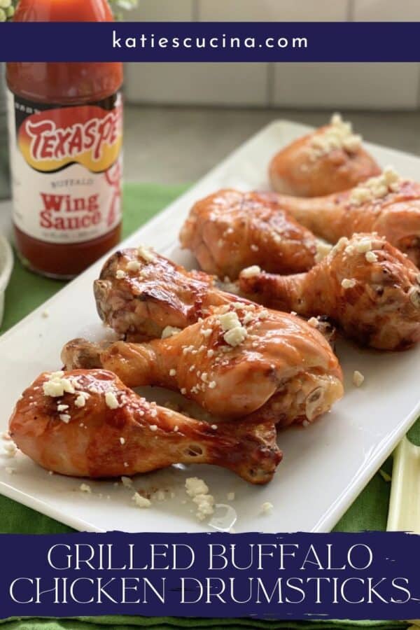 Grilled Buffalo Chicken Drumsticks on a white platter with text on image for Pinterest.
