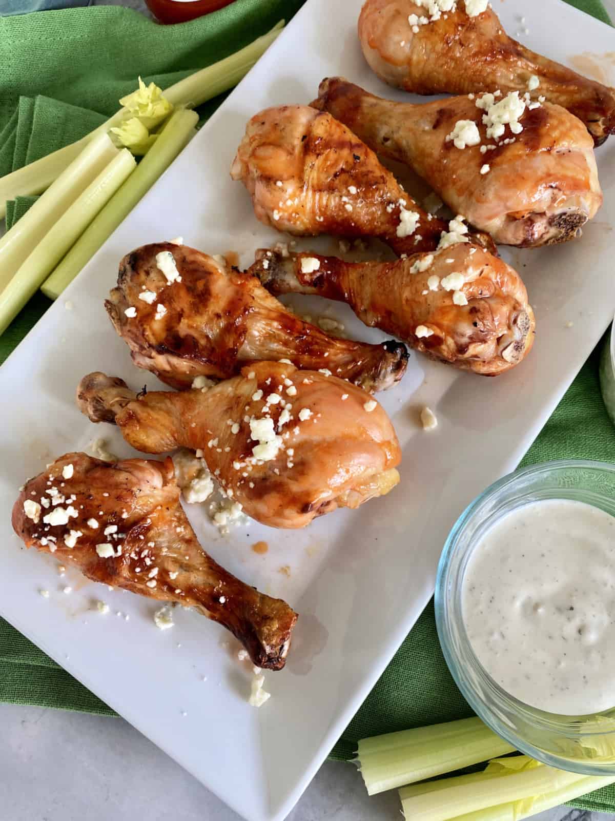 Top view of a white platter filled with Grilled Buffalo Chicken Drumsticks with bleu cheese.