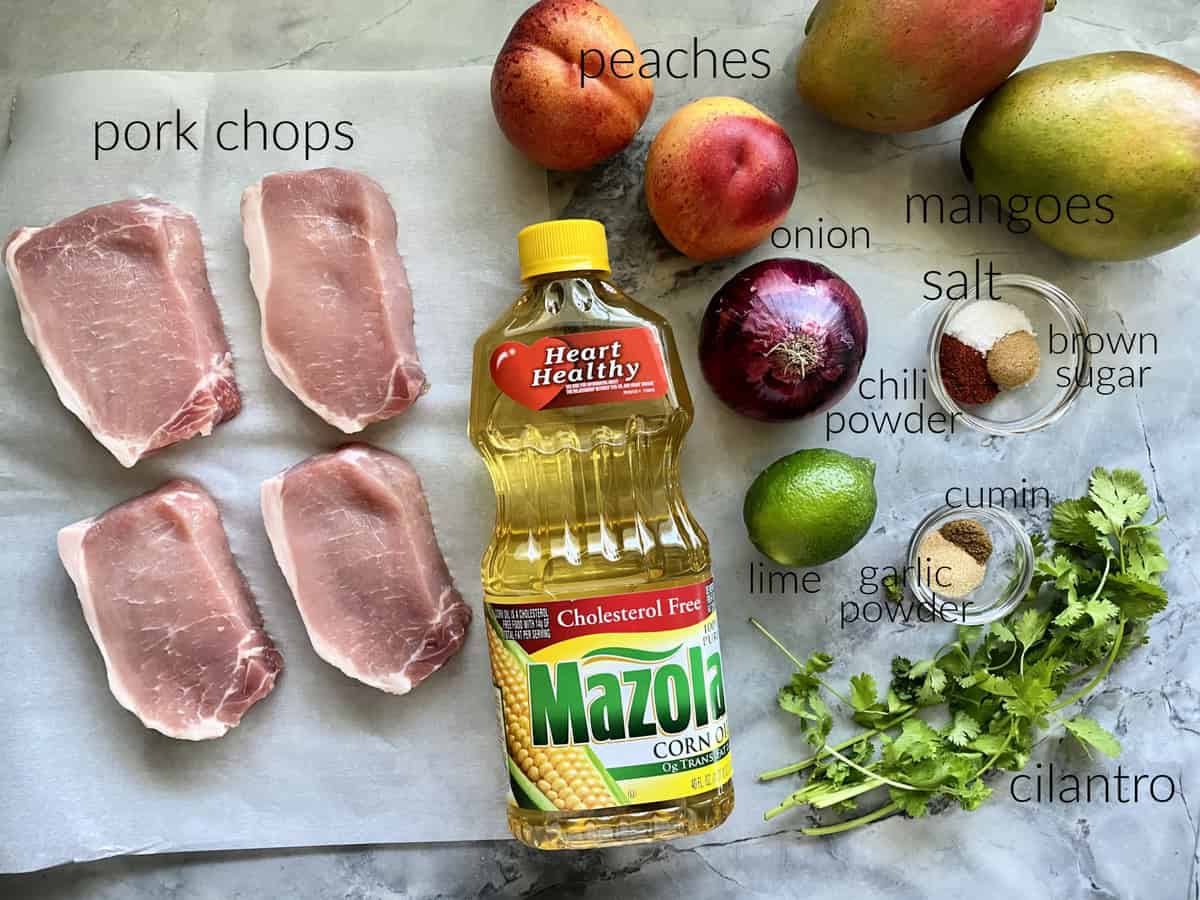 Ingredients: pork chops, Mazola® Corn Oil, peaches, onion, lime, garlic powder, cilantro, seasonings, and mangoes.