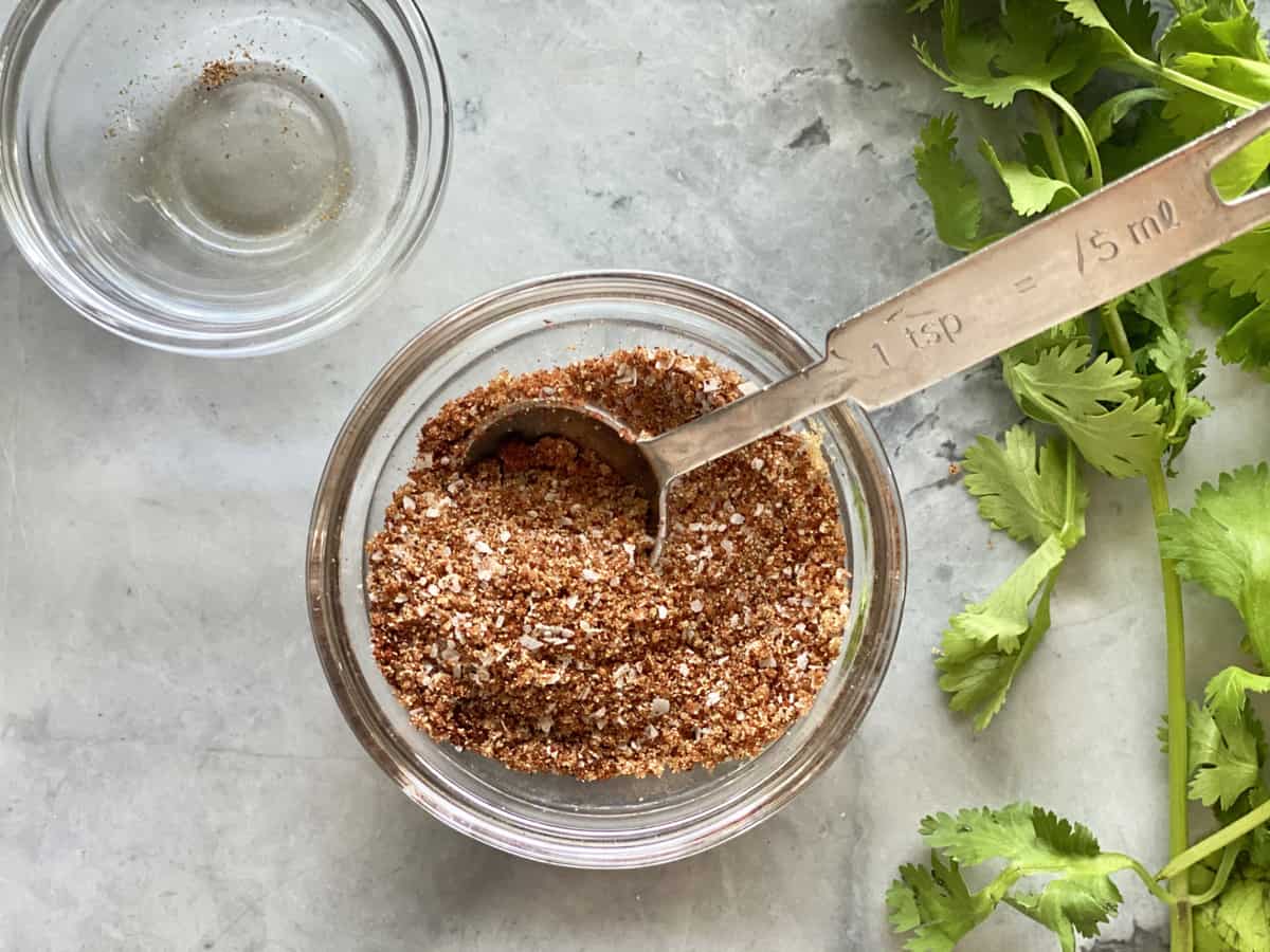 Glass bowl with spices in it with a teaspoon in the bowl.