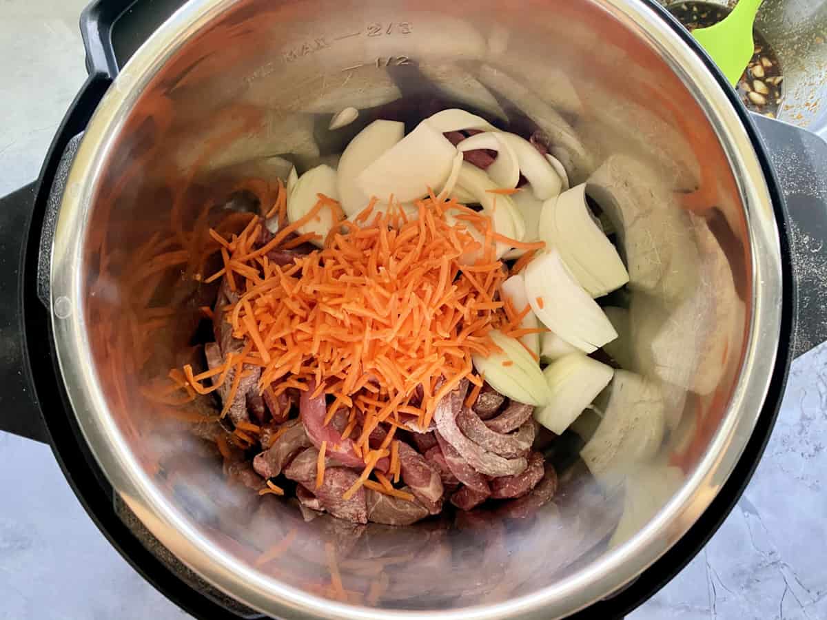 Top view of of beef, shredded carrots, and onions.