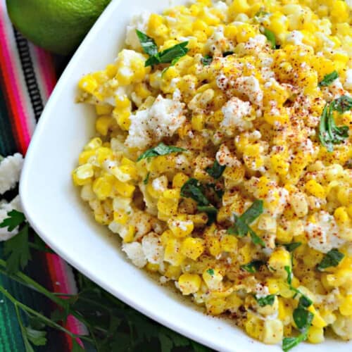 White square bowl filled with corn, cheese, and herbs.