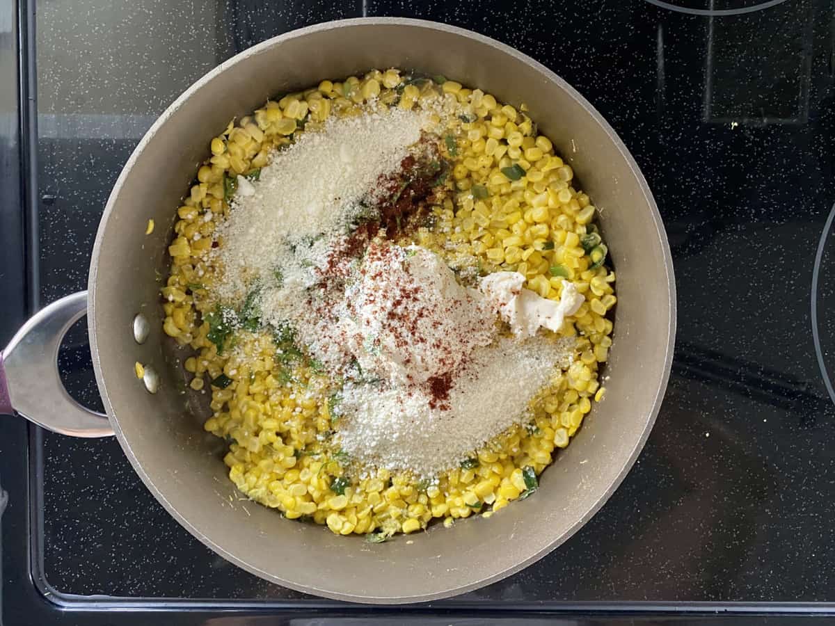 Top view of a skillet full of corn, mayonnaise, chili powder, and cotija cheese.