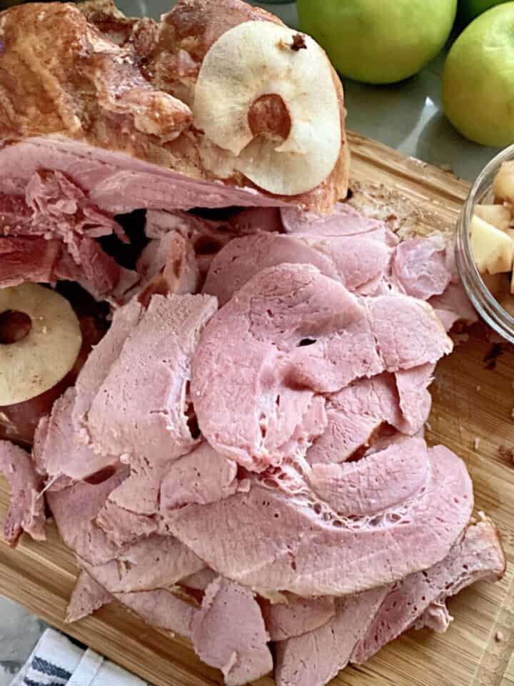 Wood cutting board with slices of ham.