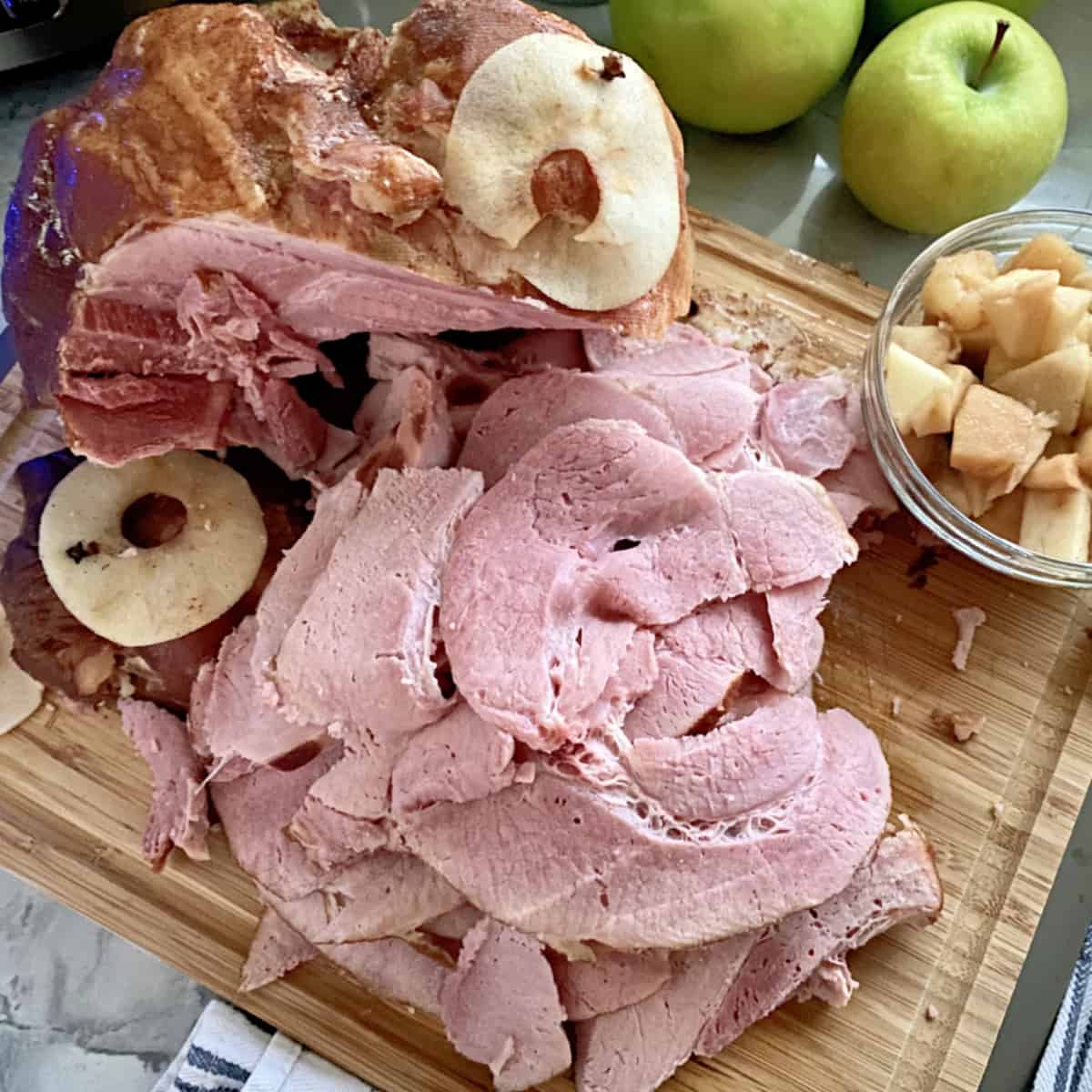 Wood cutting board with slices of ham.