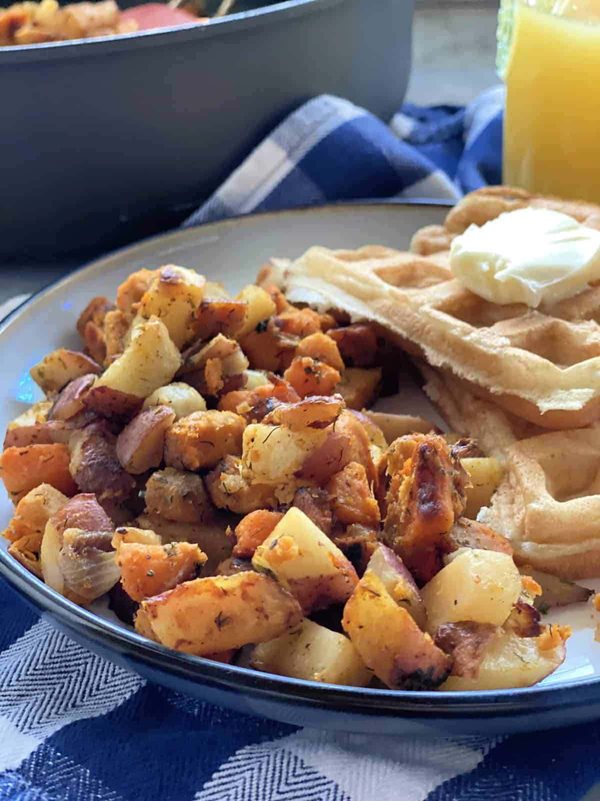 White plate filled with Southern Breakfast Potatoes with buttermilk waffles.