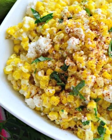 White square bowl filled with corn, cheese, and herbs.