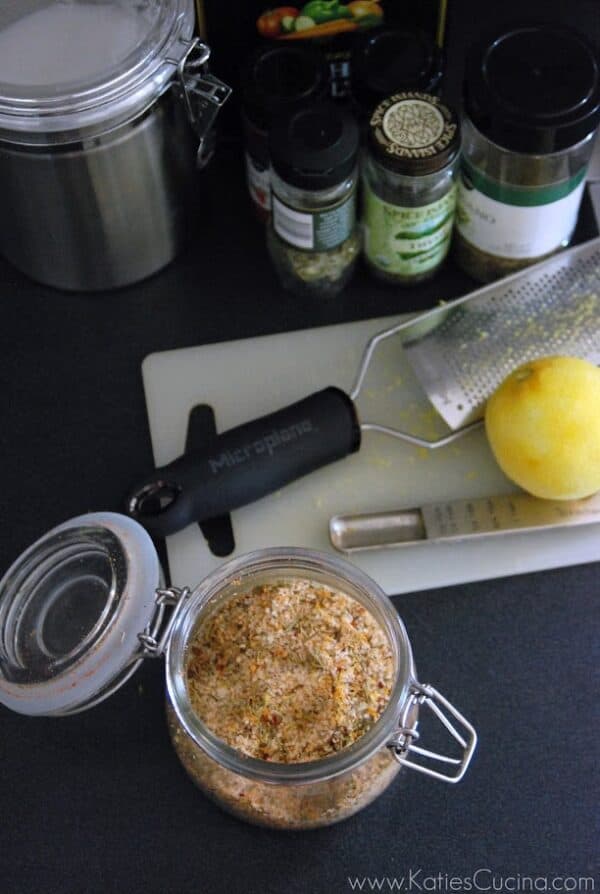 Top view of a glass jar filled with a seasoning with spices in background.