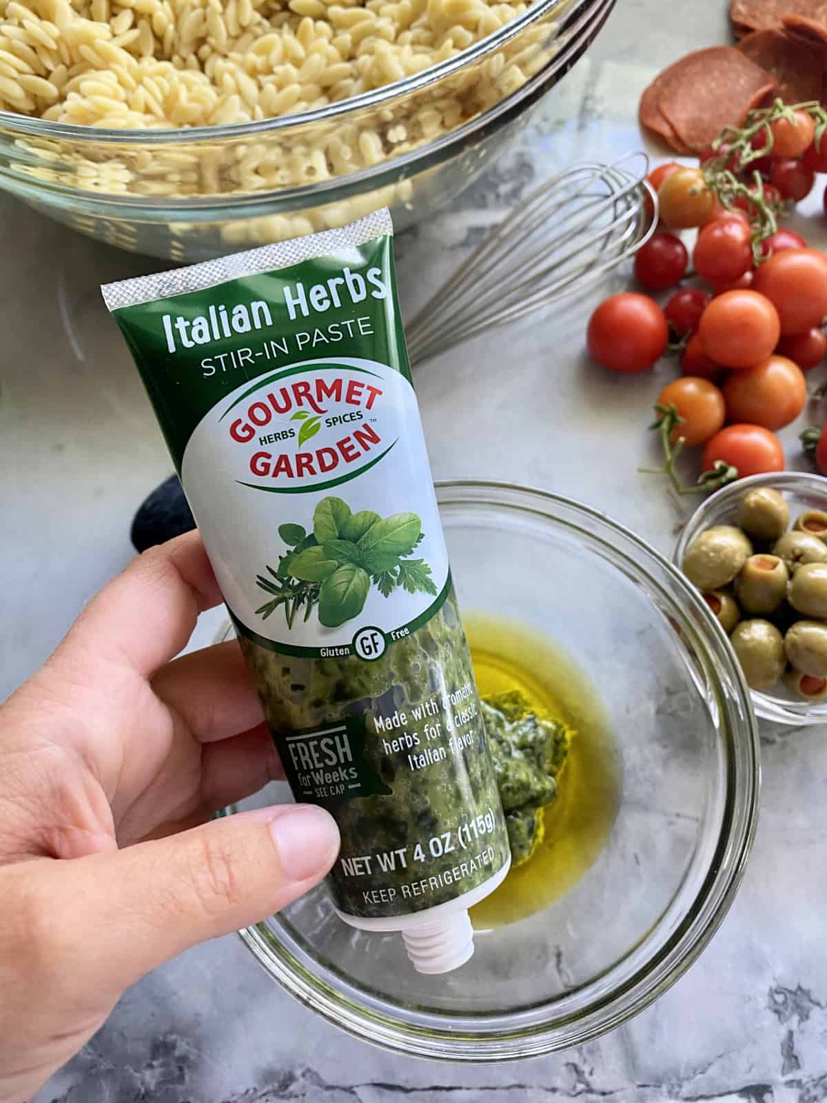 Orzo Antipasto Salad via KatiesCucina.com #FlavorsOfSummer Female hand holding Italian Herb Gorumet Garden Stir-In Paste.