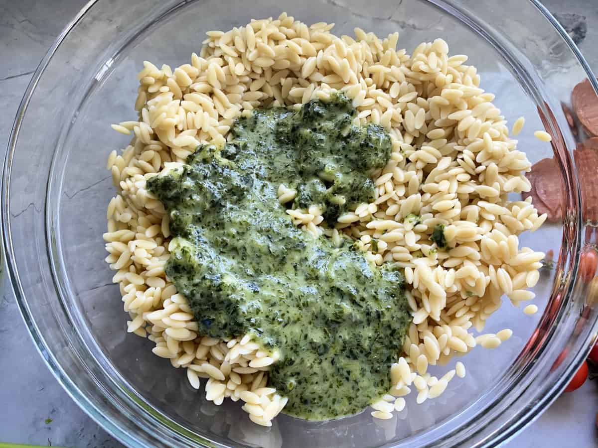 Top view of a glass bowl filled with orzo and Italian herb dressing.