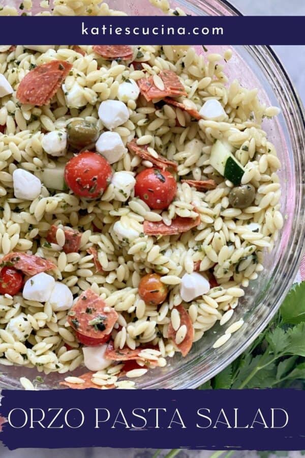 Top view of a glass bowl filled with Orzo Pasta Salad with recipe title text on image for Pinterest.