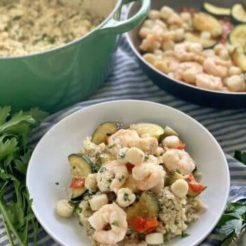 White bowl filled with risotto, shrimp, bay scallops, and zucchini.