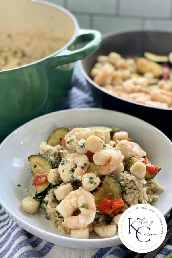 White bowl, green pot and skillet in background all filled with Shrimp and Scallop Risotto.