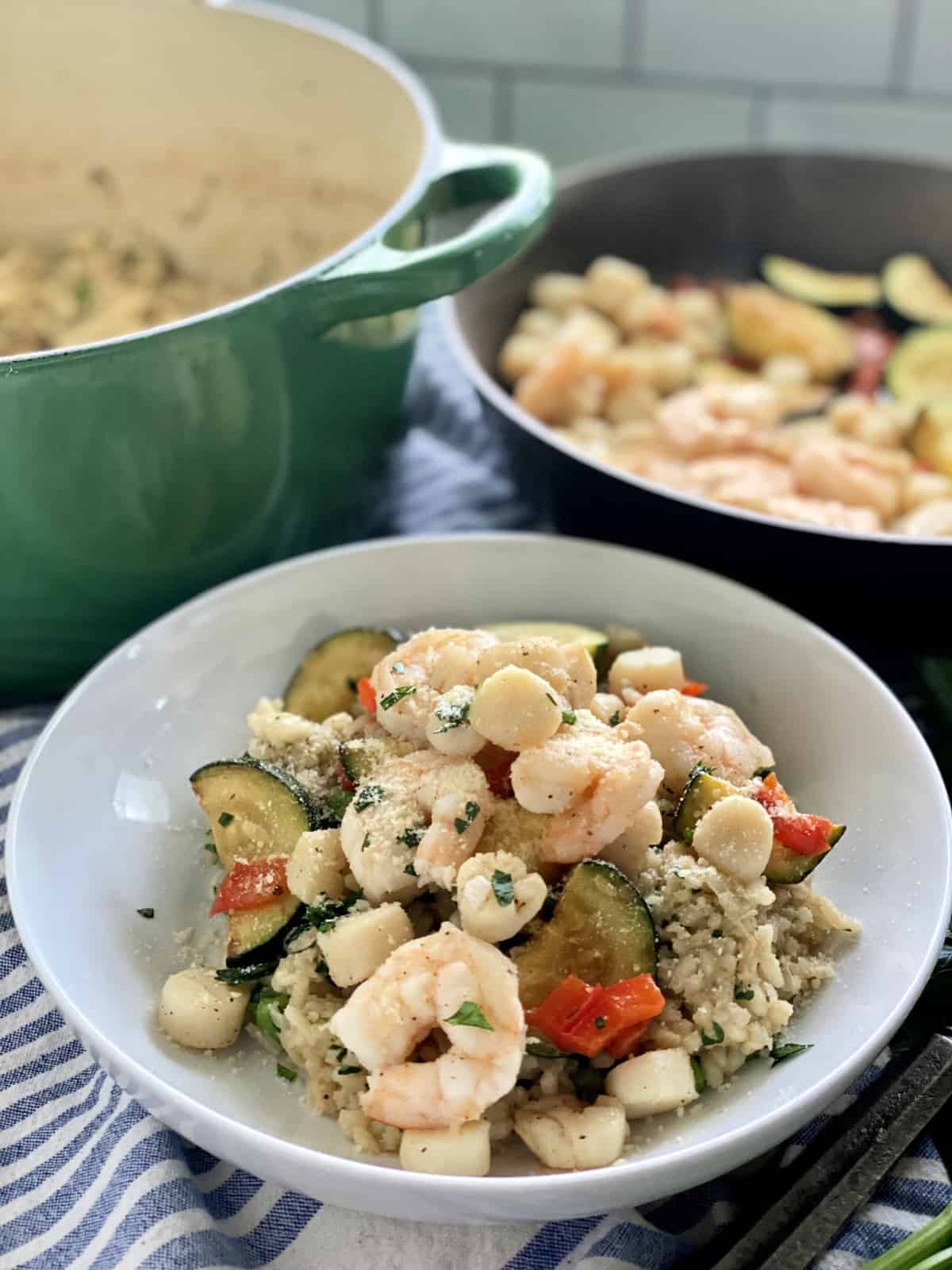 White bowl filled with shrimp, scallops, zucchini, and peppers.