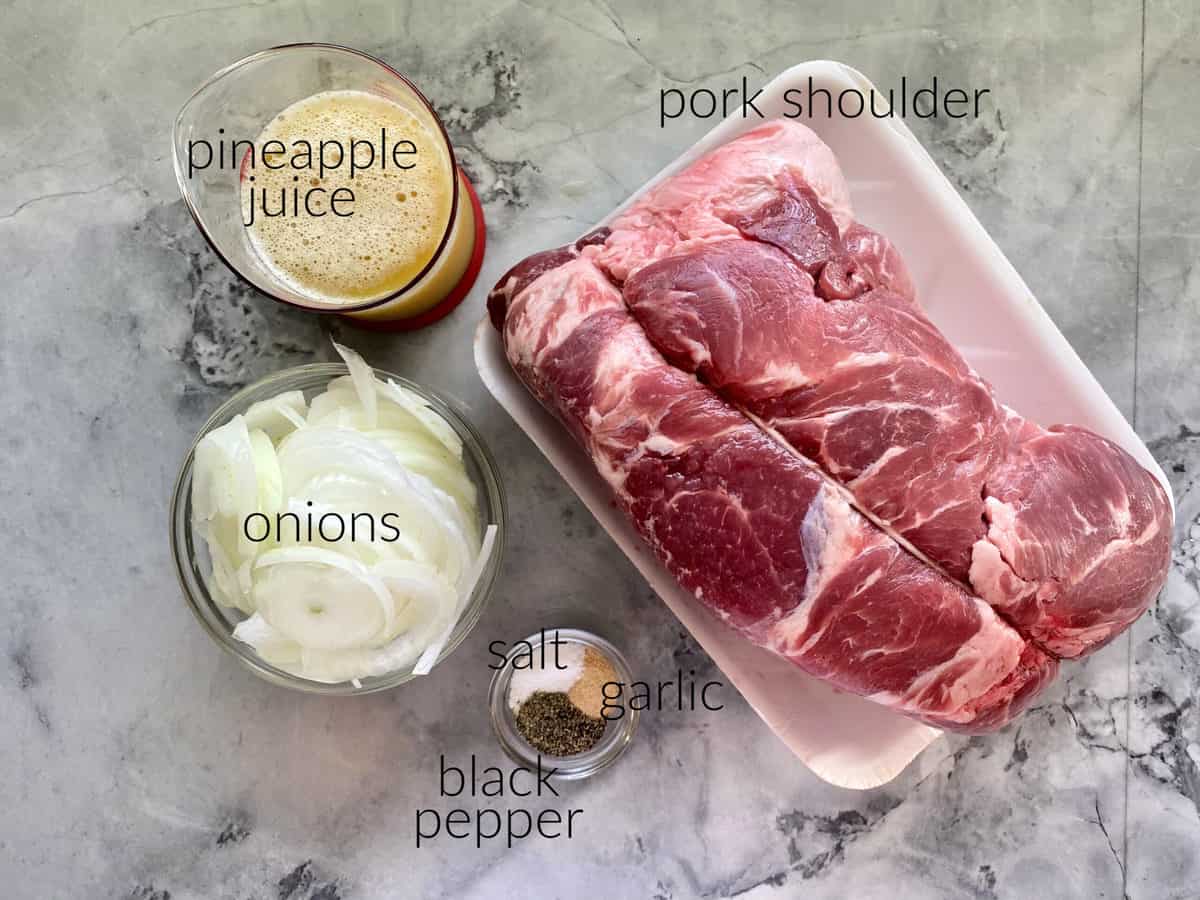 Ingredients on marble countertop: pork shoulder, onions, pineapple juice, salt, pepper, and garlic powder.