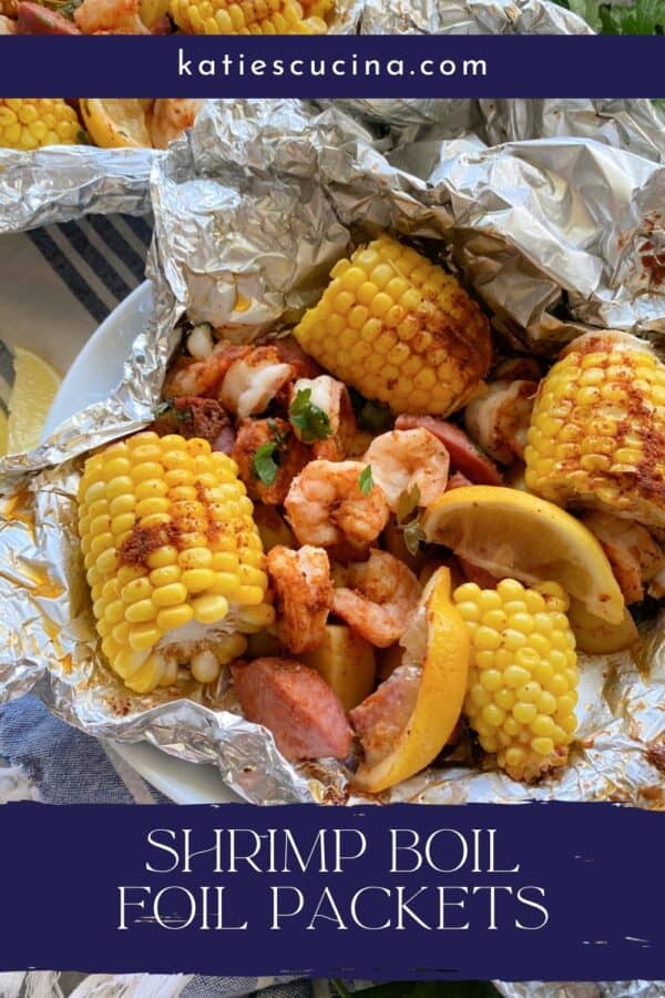 Close up of a foil packet filled with corn, shrimp, sausage, lemon wedges, and potato with text on image for Pinterest.