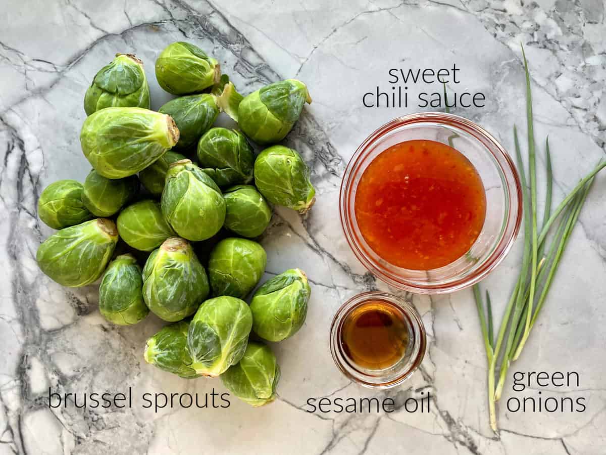 Ingredients on counter; brussel sprouts, sweet chili sauce, sesame oil, and green onions.