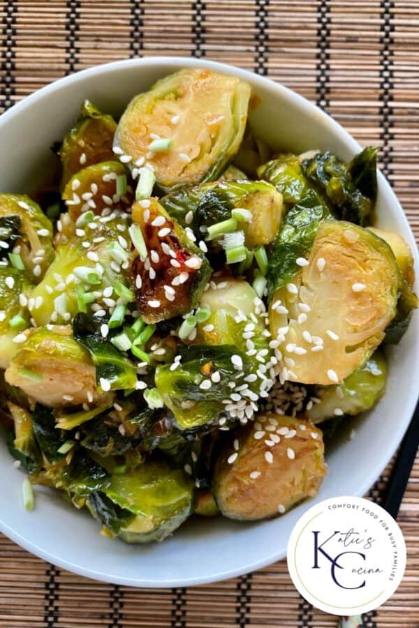 Top view of a bowl filled with sliced brussel sprouts with log on right corner.