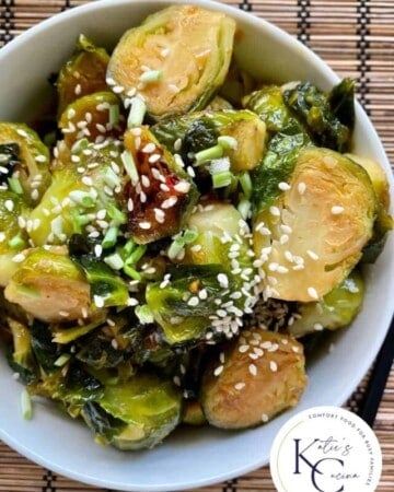 Top view of a bowl filled with sliced brussel sprouts with log on right corner.