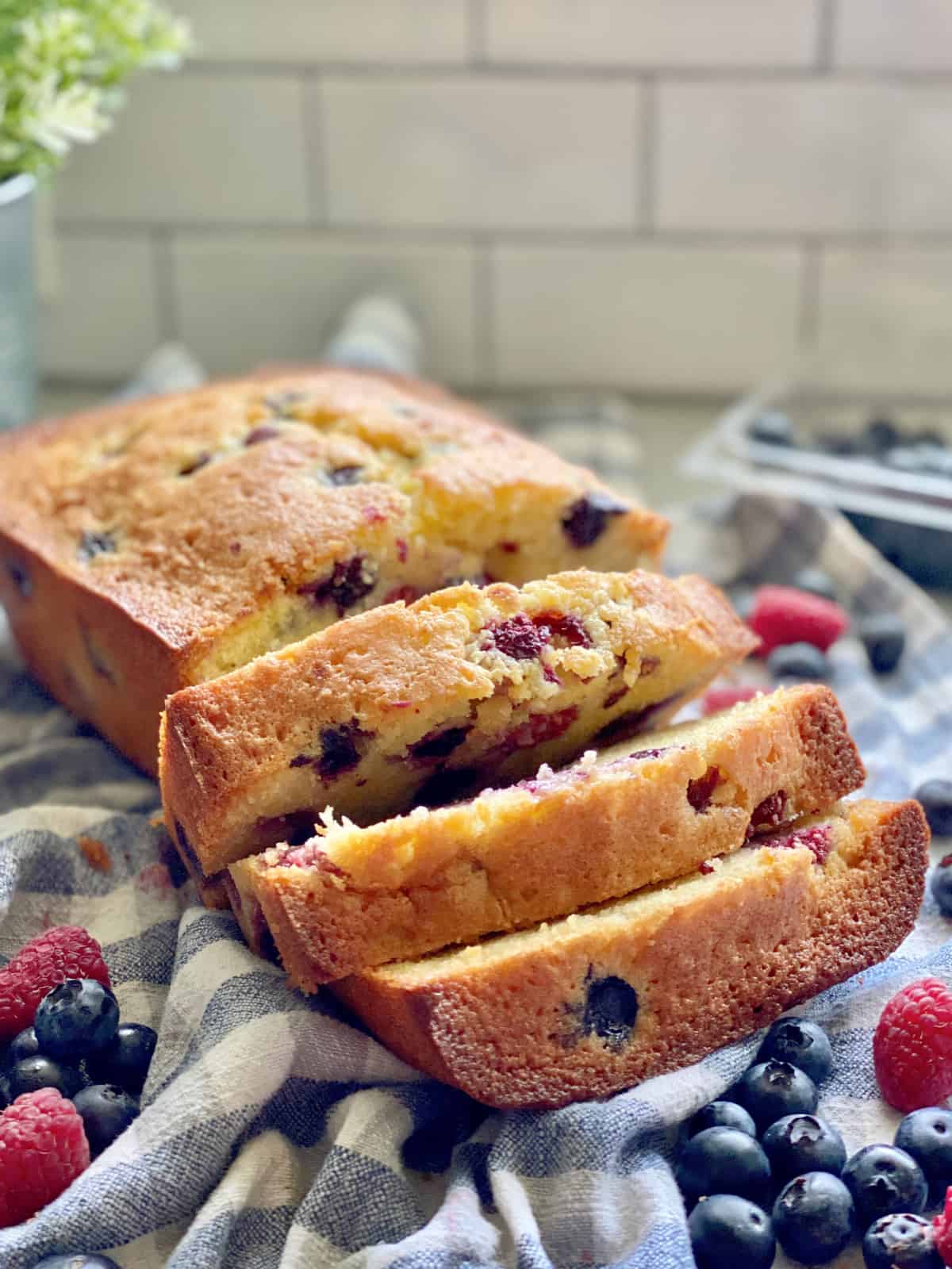 Berry Cornmeal Pound Cake with 3 slices on a white and blue checkered cloth.