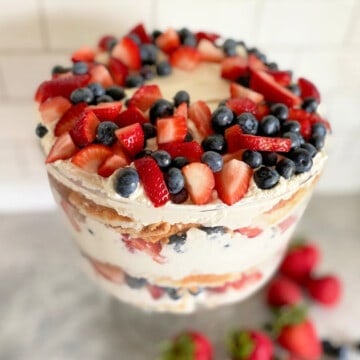 Glass bowl filled with whipped cream, cake, and berries.