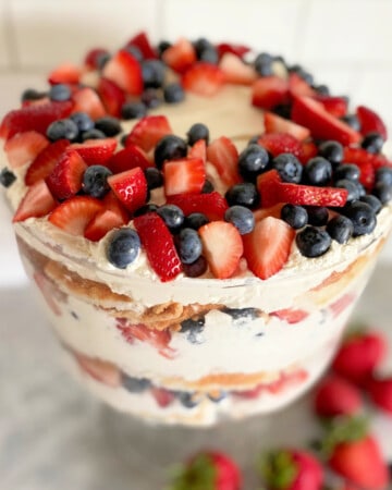 Glass bowl filled with whipped cream, cake, and berries.