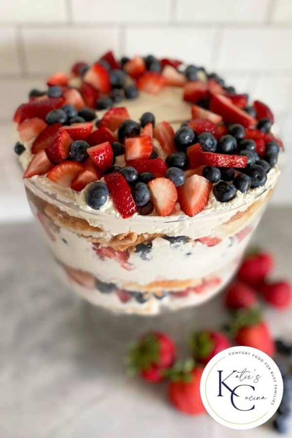 Top view of a glass bowl of a Berry Trifle with a logo on right corner.