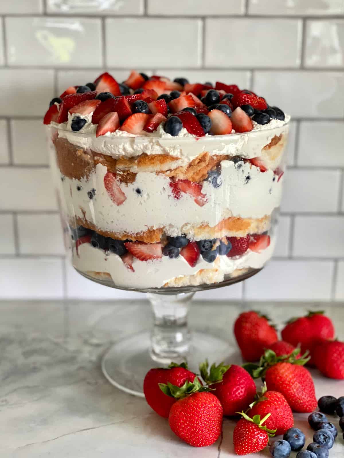 Glass trifle bowl layered with cake, whipped topping, and fresh berries.