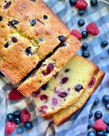 Top view of a Berry Cornmeal Pound Cake with three slices resting on a blue and white checkered cloth.