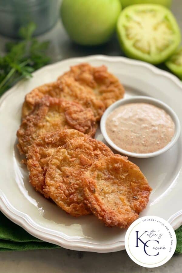 Six golden Fried Green Tomatoes on a white plate with logo on right corner.