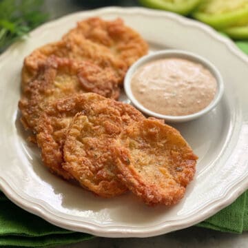 6 Fried Green Tomatoes on a white plate with a dipping sauce.