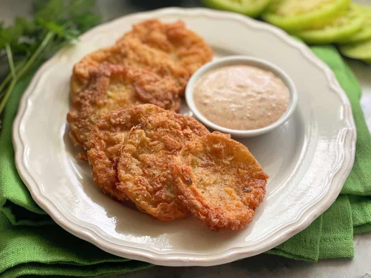 6 Fried Green Tomatoes on a white plate with a dipping sauce.