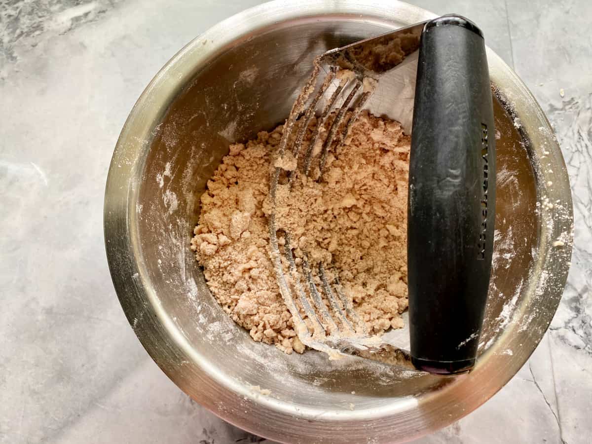 Top view of a steel bowl with a pastry cutter and stresuel topping.