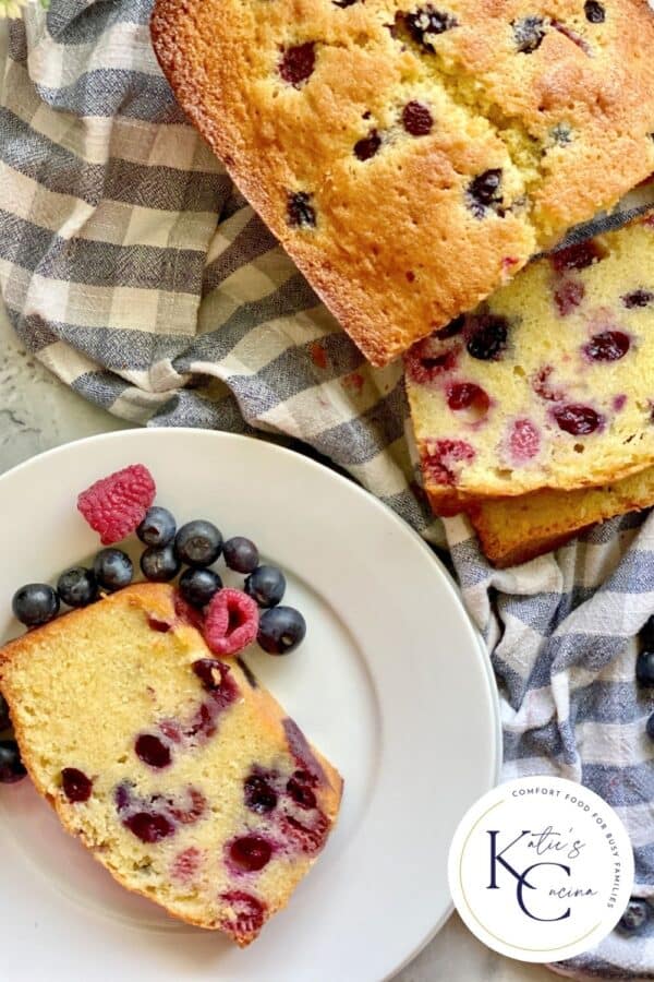 Top view of a Berry Cornmeal Pound Cake with slices on a dish cloth and logo on the right corner.