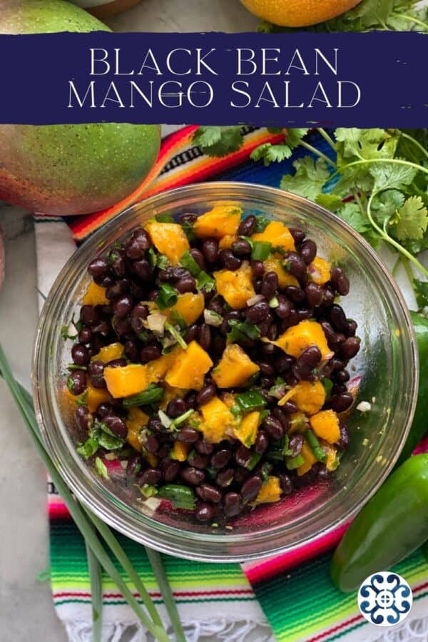 Top view of a glass bowl filled with black bean mango salad with recipe title text on image.