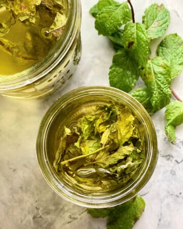 Top view of a glass jar filled with mint sprigs with clear liquid.