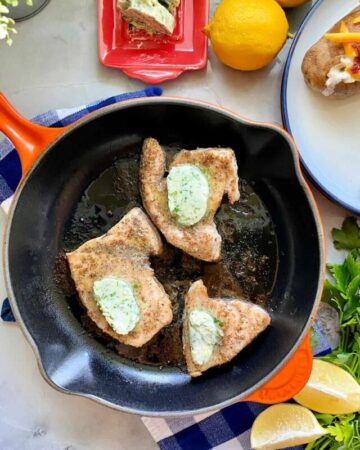 Three swordfish steaks cooking on a cast iron skillet