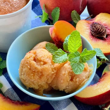 Blue bowl filled with scoops of peach sorbet with mint.