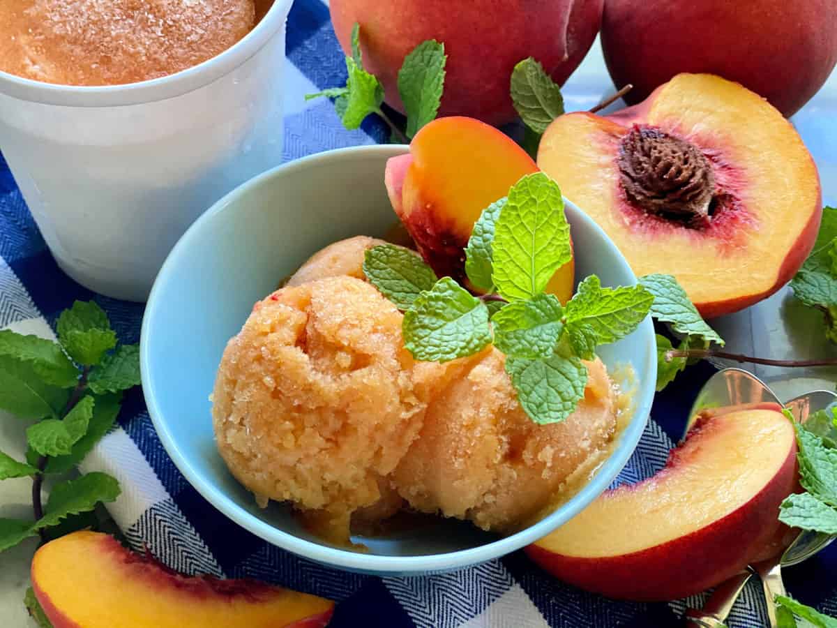 Blue bowl filled with scoops of peach sorbet with mint. 