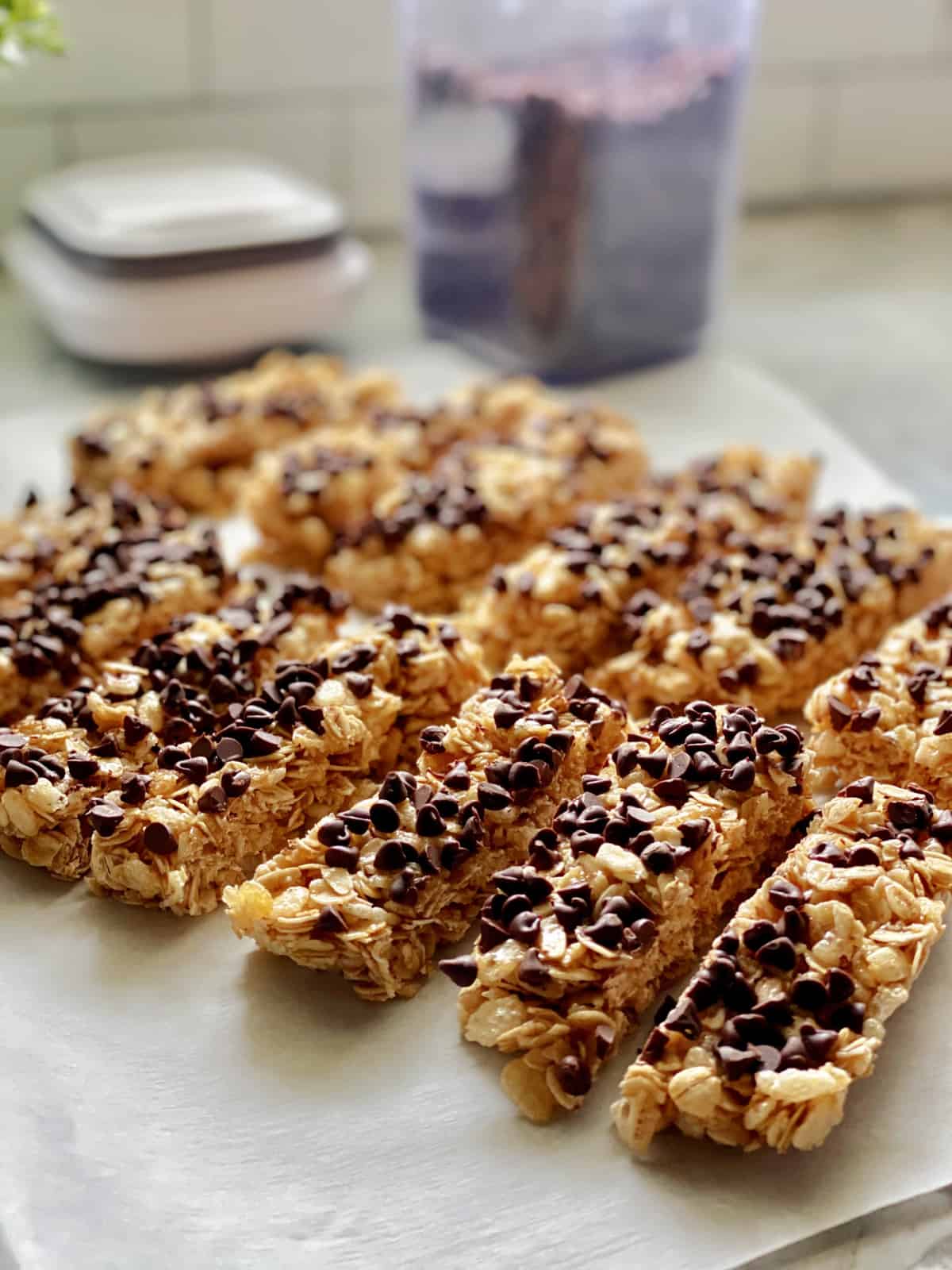 White parchment on countertop with 13 chocolate chip granola bars on top.