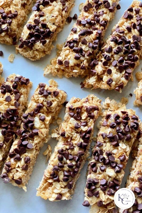 Top view of homemade Chocolate Chip Granola Bars cut and lined up on parchment paper with logo on right corner.