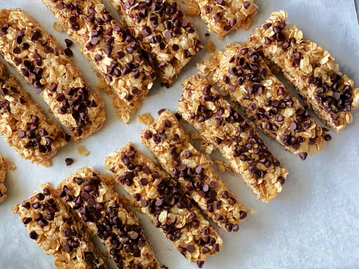 Top view of 13 granola bars on white parchment paper with mini chocolate chips on top.