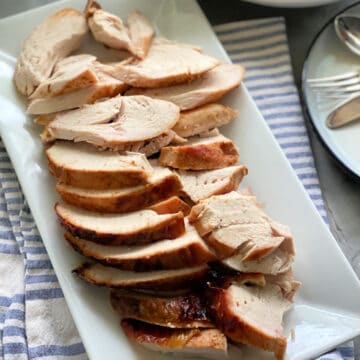 Top view of sliced turkey breast on a white platter.