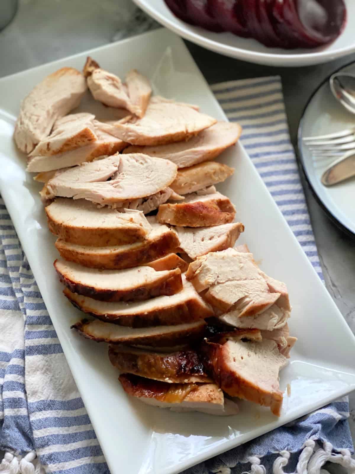 Top view of sliced turkey breast on a white platter.