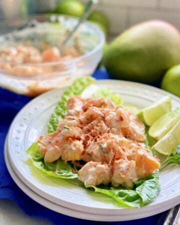 White plate with lettuce and Mango Shrimp Salad on top.