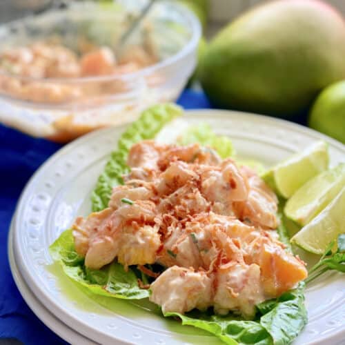 White plate with lettuce and Mango Shrimp Salad on top.