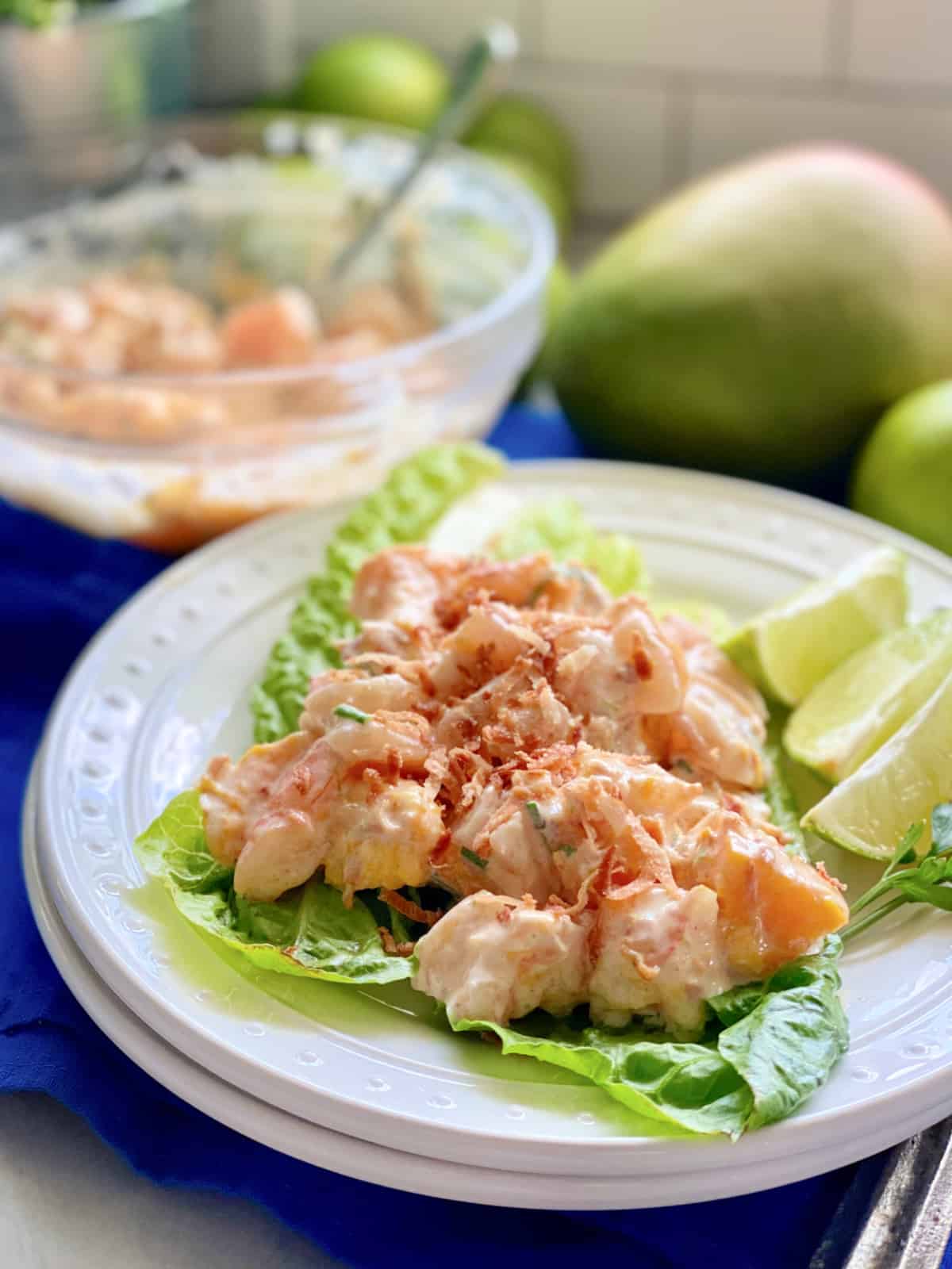 White plate with lettuce and Mango Shrimp Salad on top.